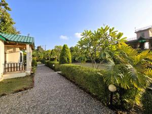 a garden with bushes and a walkway next to a building at Corbett Mid Forest House - 1 Min Walk from Dabka River in Rāmnagar