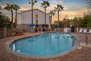 a swimming pool with palm trees and a building at Best Western Plus Tallahassee North Hotel in Tallahassee