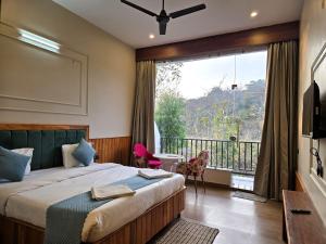a hotel room with a bed and a large window at Corbett Mid Forest House - 1 Min Walk from Dabka River in Rāmnagar