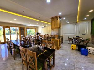 a restaurant with wooden tables and chairs in a room at Corbett Mid Forest House - 1 Min Walk from Dabka River in Rāmnagar