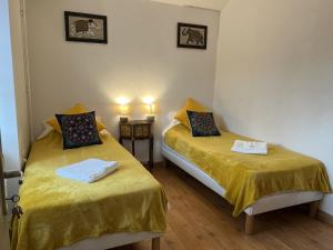 two beds in a small room with yellow sheets at Au pré du puy in Chambretaud