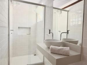 a white bathroom with two sinks and a mirror at Peixe Crew Rua das Pedras in Búzios +118 photos