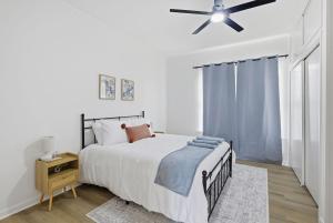 a white bedroom with a bed and a ceiling fan at The Lake Charles Charmer in Lake Charles