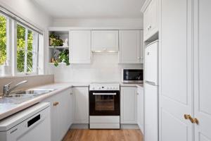 a white kitchen with a stove and a sink at Kowhai Apartment-Ground Floor in Pukekohe East