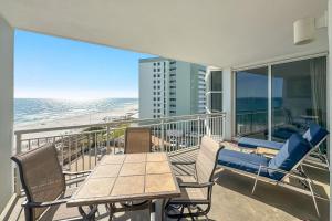 a balcony with a table and chairs and the beach at Palacio Unit 403 in Pensacola