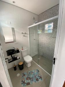 a bathroom with a toilet and a glass shower at -TROPICAL SUÍTES- ao lado do SESC-BERTIOGA in Bertioga +6 photos