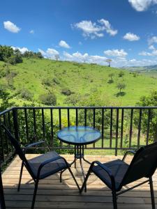 Ein Tisch und Stühle auf einer Terrasse mit Blick auf einen Hügel in der Unterkunft Carmelo Morada do Sol in Tomazina