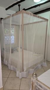 a canopy bed with white curtains in a room at Villa Tewa in Mtwapa +24 photos