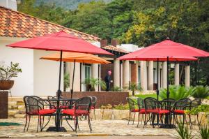 a group of tables and chairs with red umbrellas at Hotel Real Tamasopo in Tamasopo