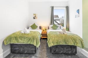 two beds in a room with a window at Comfortable 4 Bed Home - Free Parking & Brand New Bathroom in Denton