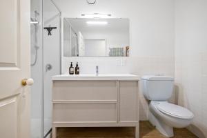 a white bathroom with a toilet and a sink at Kowhai Apartment-Ground Floor in Pukekohe East