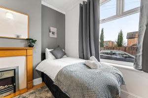 a bedroom with a bed and a fireplace and a window at Comfortable 4 Bed Home - Free Parking & Brand New Bathroom in Denton