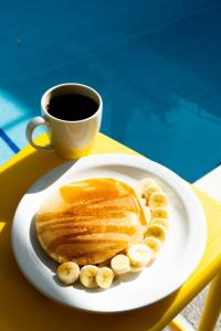 a white plate with pancakes and a cup of coffee at El Machico Hostel in Panama City