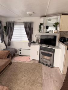 a living room with a tv and a fireplace at Hoopers Hideaway Caravan Rental SetonSands 2 in Port Seton
