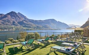 a group of chairs sitting on the grass with a view of the water at Bellagio Village - Holiday Apartments by the Lake - Seasonal Warm Pool and Sauna in Oliveto Lario