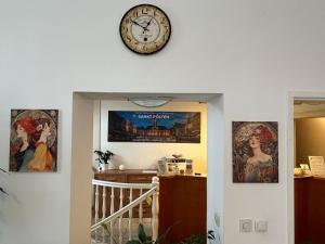 a clock on a wall above a hallway with posters at Mariazellerhof Room 014 in Sankt Pölten +3 photos