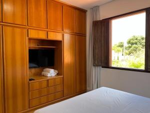 a bedroom with a cabinet with a television and a window at Casa - Conceito in Bom Jesus da Lapa