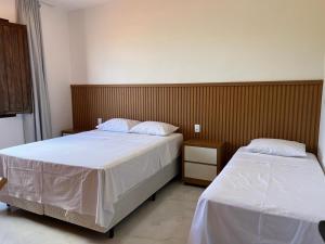 a bedroom with two beds with white sheets at Casa - Conceito in Bom Jesus da Lapa