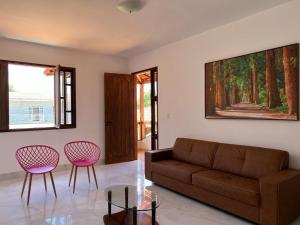a living room with a couch and two pink chairs at Casa - Conceito in Bom Jesus da Lapa