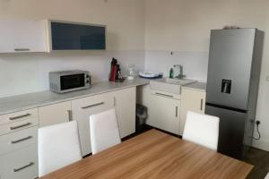 a kitchen with white cabinets and a stainless steel refrigerator at Sleek Apartment in Troisdorf in Troisdorf +6 photos