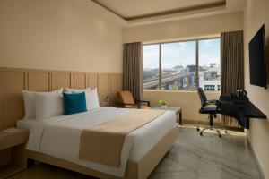 a hotel room with a bed and a desk and a window at The Fern Residency Bengaluru, Yeshwanthpur, Series by Marriott in Bangalore +76 photos