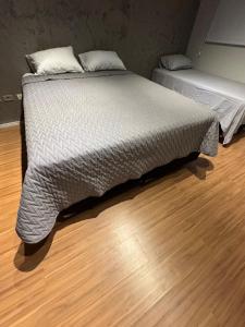 two beds in a room with a wooden floor at Home Tatuapé in São Paulo