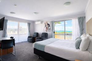 a bedroom with a bed and two chairs and a window at BKs Premier Motel Esplanade in Lower Hutt +40 photos