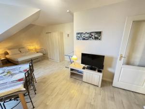 a living room with a television and a bed and a table at Appartement centre Compiègne in Compiègne