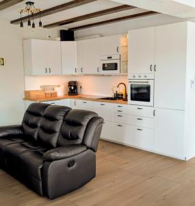 a black leather chair in a kitchen with white cabinets at Conacu Lacului Brebu in Brebu Mînăstirei