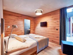 a bedroom with wooden walls and a bed with a lamp at Smaragdresort Gipfelstürmer in Brandberg