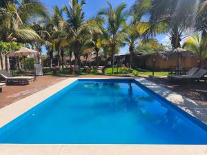 a large swimming pool with palm trees in the background at Punta Pacífico Bungalows Máncora in Máncora
