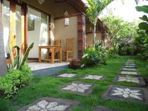 a garden outside a house with a table and chairs at Made Taro - Menjangan Homestay in Banyuwedang