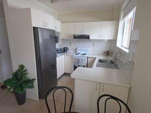 a kitchen with white cabinets and a stainless steel refrigerator at Crystal Waters 7 Ocean Corridor Views, Restaurants, Town Centre in Forster