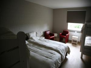 a bedroom with a bed and two red chairs at Countryside holiday home in Gijverinkhove