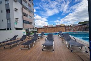 a deck with chairs and a swimming pool on a building at Apto Aquarius - Piscinas Aquecidas, Hidro e Lazer Total - até 5 Pessoas in Caldas Novas
