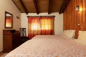 a bedroom with a bed and a dresser and windows at Cabañas Sierra Verde in Cedro