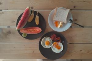 a table with two plates of eggs and a bowl of fruit at Wildcat hostel Yala in Kataragama