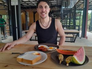 a man sitting at a table with a plate of food at Wildcat hostel Yala in Kataragama