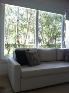 białą kanapę w pokoju z dużym oknem w obiekcie Departamento Green Park w mieście Punta del Este