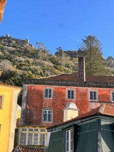 an old red brick building with a hill in the background at Sintra Central Apartment in Sintra