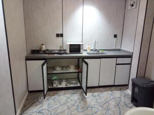 a small kitchen with a sink and a microwave at ﻣﺆﺳﺴﺔ ﺷﻘﻖ ﺍﻟﻘﺎﺭﺍﺕ ﺍﻟﺴﺒﻊ ﺍﻟﻤﺨﺪﻭﻣﺔ in Raḩīmah