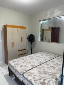 a bedroom with a bed with a mirror and a window at Casa Guriri in São Mateus