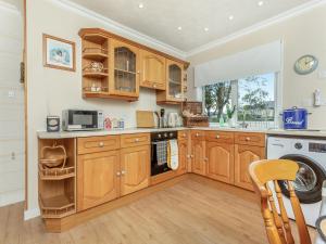 a kitchen with wooden cabinets and a washer and dryer at Tanera in Wick