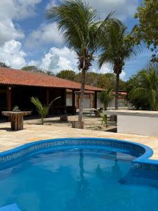 a pool in front of a house with palm trees at Hotel Fazenda Alta Vista in Fortim