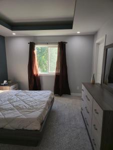 a bedroom with a bed and a dresser and a window at The Lots home in Winnipeg