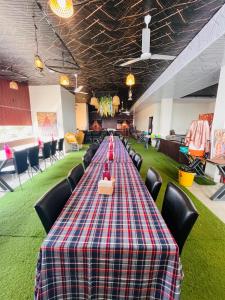 a long table with chairs in a room with green carpet at Hotel Basil Inn in Ujjain