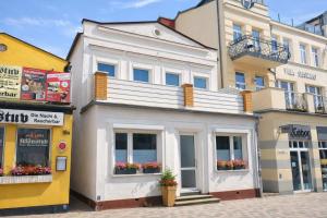 a white building with flowers in front of it at Haus Wilbrand Ferienzimmer 1 in Warnemünde +4 photos