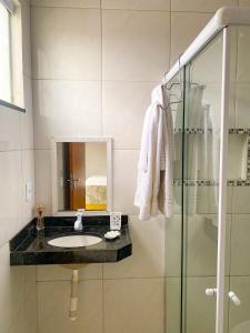 un baño con lavabo y ducha de cristal en Eficiência - Casa Dascli - Sua Casa em Camocim, en Camocim