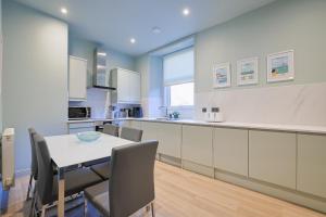 a kitchen with white cabinets and a table and chairs at Gordon's Getaway Lux in Oban +29 photos