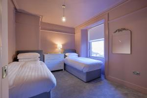 two beds in a room with a mirror and a window at Gordon's Getaway Lux in Oban